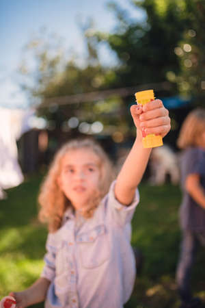 Little girl blowing soap bubbles outdoors