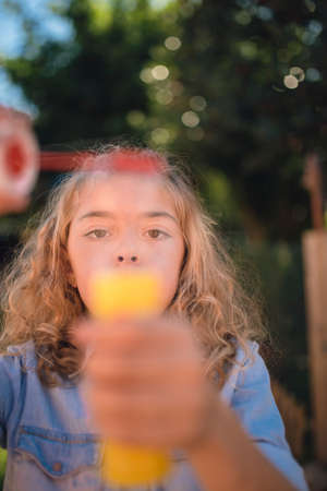 Little girl blowing soap bubbles outdoors