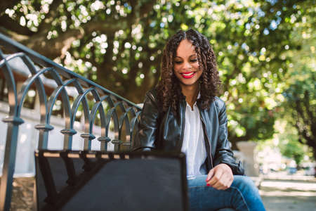Portrait of a Latin American Afro Woman using her laptop in the park.の写真素材