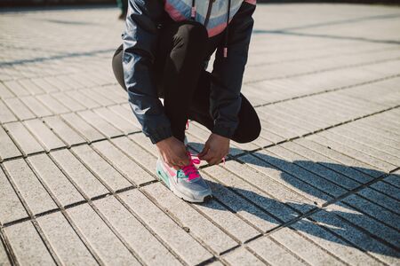 Female jogger tying her running shoes preparing for a jog outdoorsの写真素材