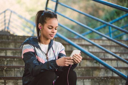 Beautiful hispanic woman listen music after running on a stairs