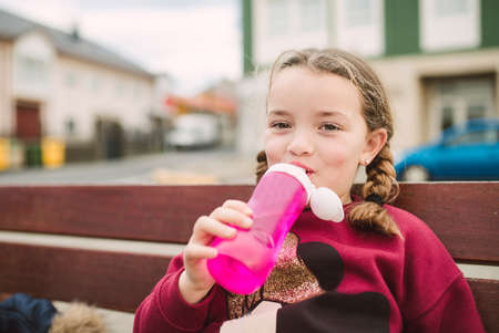 Little blonde girl drinking water in the parkの写真素材