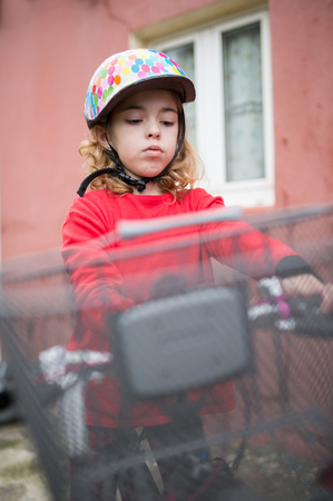 Little girl with her bicycle outdoors. She is looking down.の写真素材