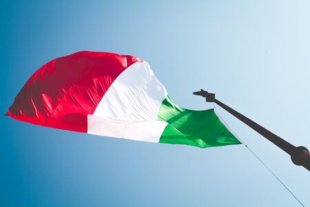 Flag from Italy waving in the blue sky a sunny day. Nation and Italian concept