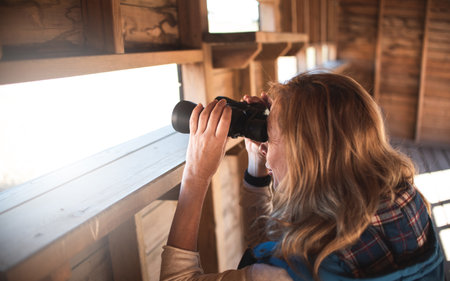 Girl in nature with binoculars doing outdoors activities. Searching, sightseeing, tourism, discover and birdwatching concept.の写真素材