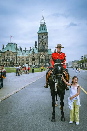 Parliament Hill, Ottawa, Ontario, Canada, Aug 2005 - Female Royal Canadian mounted police officer on horseback and a little friendly girl by her sideのeditorial素材