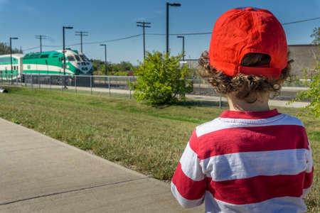 Toronto, Canada, October 2017 - Little boy wearing red striped shirt and red baseball cap watches as...