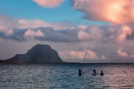 Local Fishermen in the sea with a mountain in the backgroundの写真素材