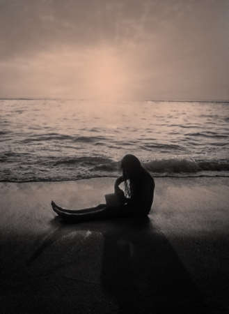 Girl in silhouette sitting and playing on the beach