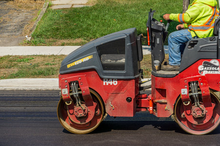 Toronto, Canada, September 2022 - Red road roller paving newly laid asphalt. Paving vehicle. Road...