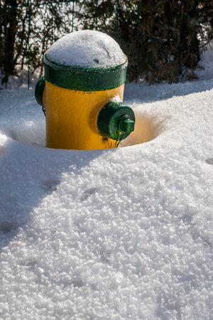Vertical shot of fire hydrant partly covered with snow after a snow stormの写真素材