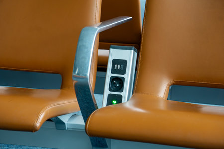 Battery charger power socket for cell phone between seats in waiting lounge at the airport. Free cell phone charging facilityの写真素材