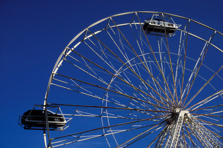 Ferris wheel on clear blue sky displaying vehicle modelの写真素材