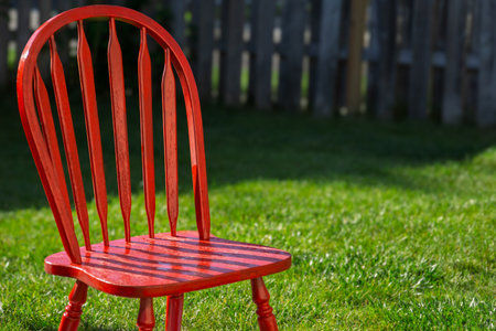 Bright red wooden chair on green lawn outdoorsの写真素材