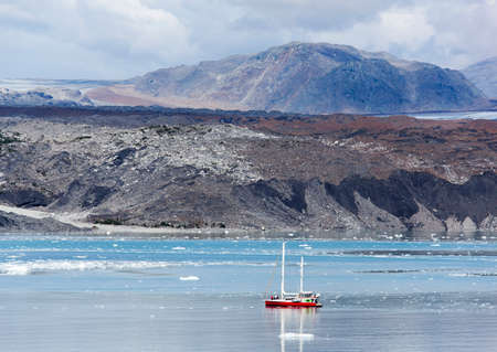 The boat sailing along the old glacier that turned it's color into black (Glacier Bay National Park, Alaska).の写真素材