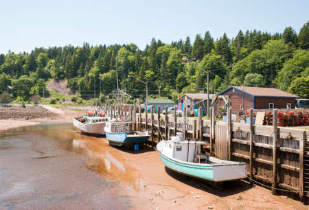 Boats are resting during the low tide in high tide famous St. Martins village (New Brunswick, Canada).の写真素材