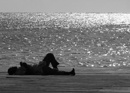The homeless man laying down by the sea on a hot day in Bridgetown, Barbados.の写真素材