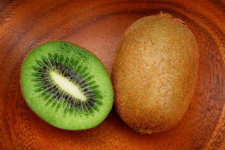 Cut ripe kiwi fruit on a wooden plate                                の写真素材