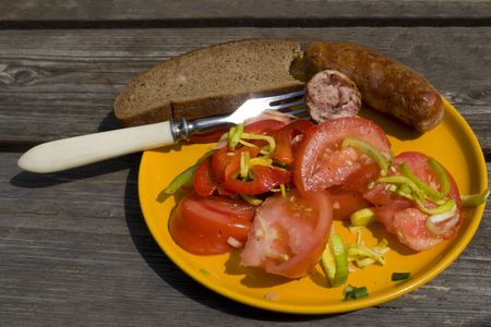 Tomato salad with sausage on the yellow plate の写真素材