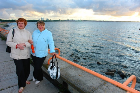 Two adult women walking on sea coast at autumn sunsetの写真素材