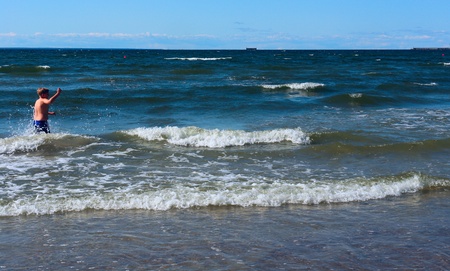 Boy enjoys the waves of the beautiful seaの写真素材