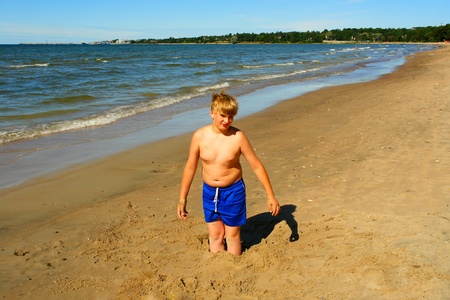 Young guy playing in the sand on the beach of Baltic Seaの写真素材