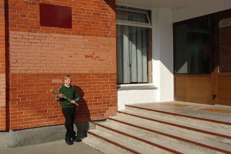Schoolboy with a bouquet of flowers standing near the school 