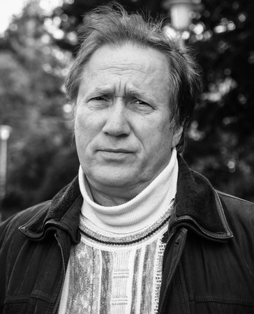 Black and white close up portrait of a mature man in deep thought.