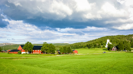 Farmland cultivated in the mountains of Norway. Near forests visible village.の写真素材