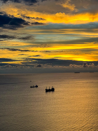 view of the sunset in the sea in Teluk Bayur, ââPadang City. from the top of the hill with weeds in the foregroundの写真素材