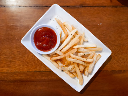 top view of crispy French fries with ketchup on a white plate. perfect for fast food, snack, and culinary themesの写真素材