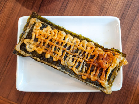 Crispy Japanese nori tacos topped with mentai or mayo sauce, served on a white rectangular plate....