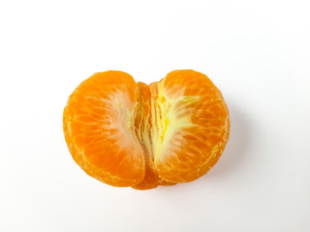 Fresh peeled mandarin orange segment close-up on white background. Juicy citrus fruit with vibrant orange color, perfect for healthy eating and food conceptsの写真素材