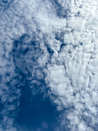 Beautiful blue sky filled with white fluffy clouds creating a textured and natural pattern. vertical backgroundの写真素材