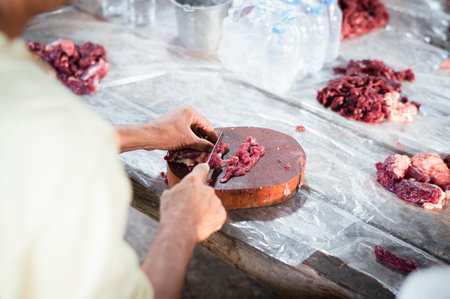 Male hand cutting fresh meat on chopping board.の写真素材
