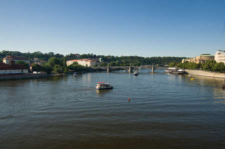 On the river Vltava from the Charles Bridge, this river is navigable which is used for tourist purposes, boats, a bridge and a clear sky are observed.の写真素材