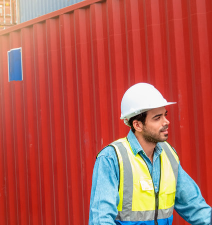 A male engineer with a safety uniform on a container background, Engineering working with a happiness conceptの写真素材