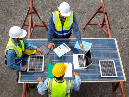Brainstorming communications of technician professional team  in safety helmets and uniforms with solar photovoltaic panels, sustainable development conceptの写真素材