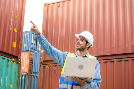 Portrait of man in safety helmets and uniforms holding laptop pointing upward with copy space for textの写真素材