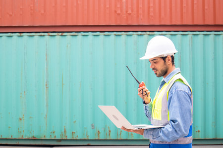 Portrait of man in safety helmets and uniforms holding laptop pointing upward with copy space for textの写真素材