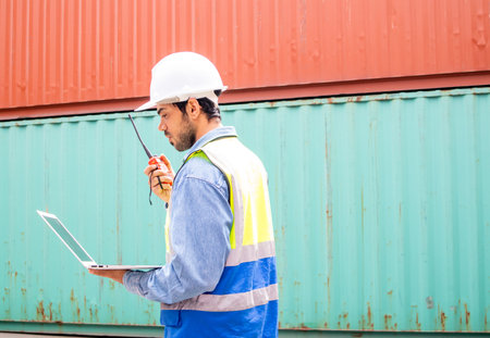 Portrait of man in safety helmets and uniforms holding laptop pointing upward with copy space for textの写真素材