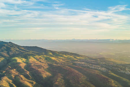 High angle aerial view of tropical mountains from above during golden hour with sky and clouds on horizonの写真素材