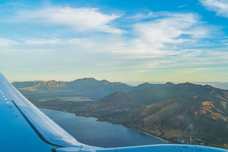 View of the tropical island of Oahu from above over wing during golden hourの写真素材