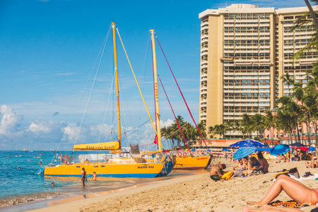 Oahu Hawaii people enjoying Waikiki beach with hotel and sailboat on beachのeditorial素材