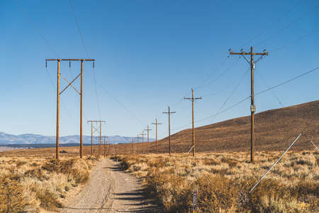 Dirt road along power poles in California high desert against blue skyの写真素材