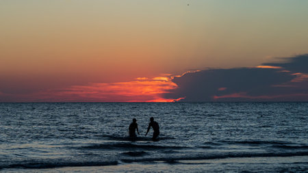 Two people playing in water on Florida beach during sunsetのeditorial素材
