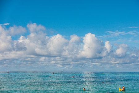 Oahu Hawaii people enjoying Waikiki in turquoise waters against sky and cloudsのeditorial素材