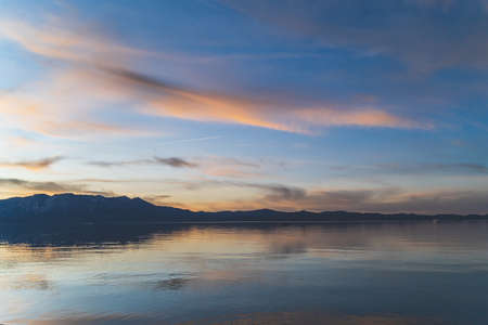 Colorful clouds reflecting in water over Lake Tahoe California after sunsetの写真素材