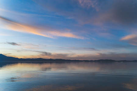 Colorful clouds reflecting in water over Lake Tahoe California after sunsetの写真素材