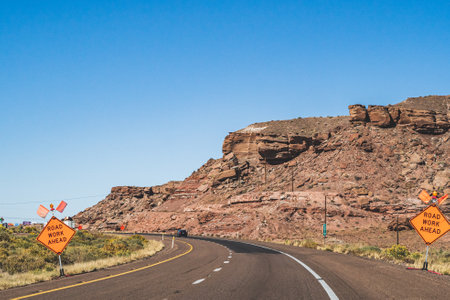 Orange Road work ahead caution signs on empty highway in southwestの写真素材